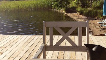 A wooden deck with a chair and a metal container.