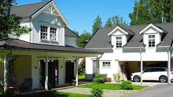 A two-story house with a covered porch, a garage, and a car parked in the driveway.
