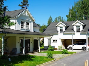 A two-story house with a covered porch, a garage, and a car parked in the driveway.