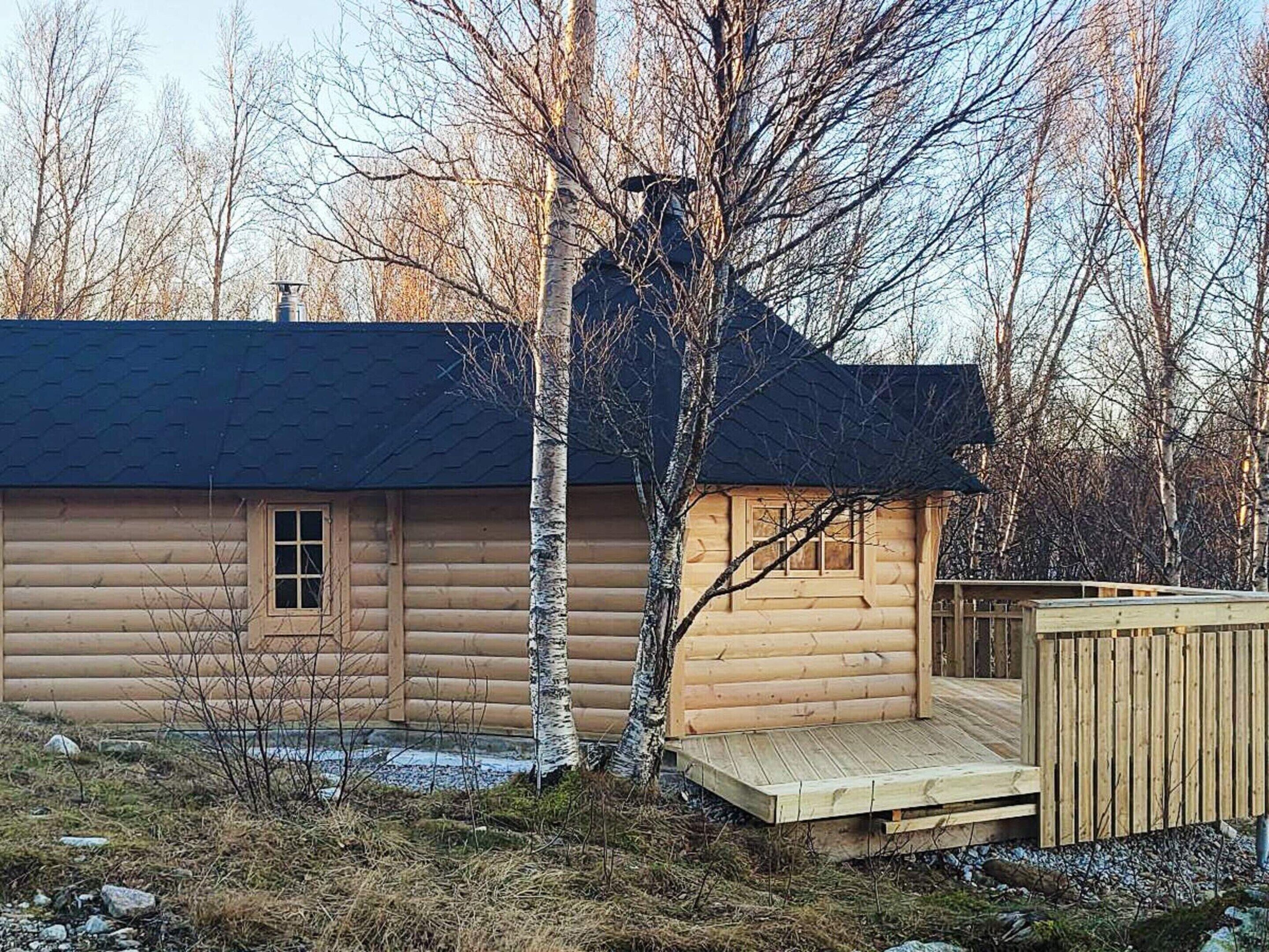 Una cabaña de troncos con una terraza y un cobertizo pequeño.