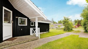 Ett svart hus med en vit veranda och en gång av tegelstenar som leder fram till huset.