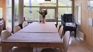 En matplats med ett träbord, stolar, en vas med blommor och en hängande taklampa.