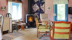 A cozy room with a fireplace, wooden furniture, and a quilted wall hanging. - 6 Person Holiday Home in Ostra Antervik-by Traum (Östra Ämtervik)