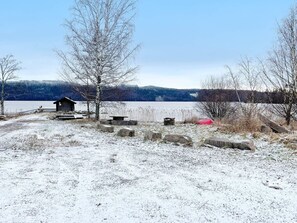 A cabin by a lake with a snow-covered ground, a small dock, and a bench. - 6 Person Holiday Home in Ostra Antervik-by Traum (Östra Ämtervik)