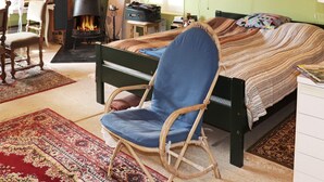 A cozy bedroom with a bed, a rocking chair, a fireplace, and a desk with a lamp. - 6 Person Holiday Home in Ostra Antervik-by Traum (Östra Ämtervik)