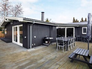 A modern outdoor deck with a dining area, a barbecue grill, and a covered seating area.