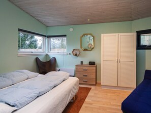 A bedroom with two beds, a dresser, a wardrobe, and a window.