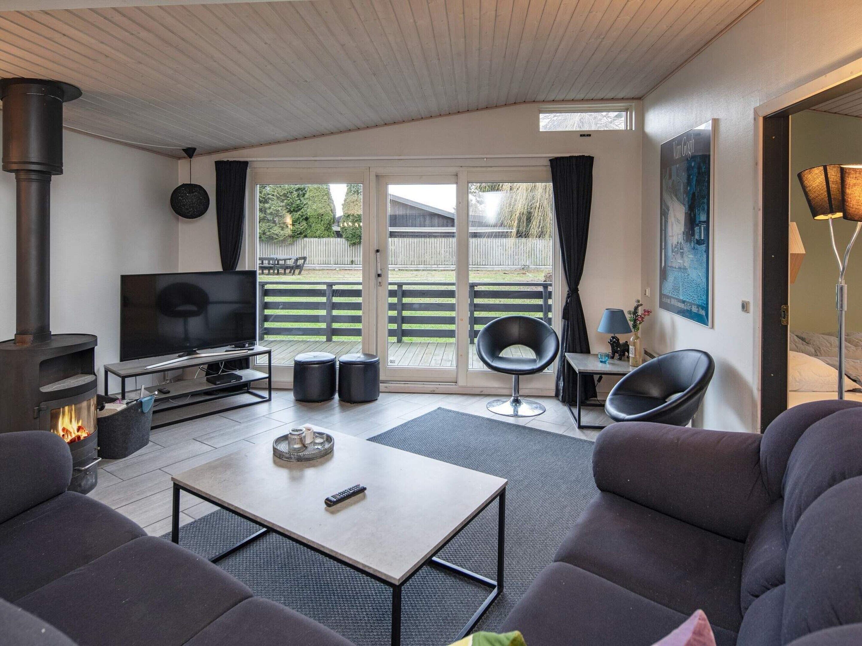 A modern living room with a fireplace, a TV, comfortable seating, and a large sliding glass door leading to an outdoor area.