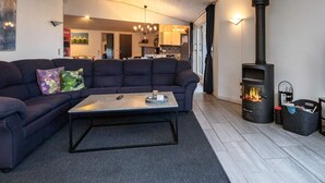 A modern living room with a sectional sofa, a coffee table, and a wood-burning stove. - 10 Person Holiday Home in Vaeggerlose-by Traum (Vaeggerlose)