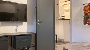A room with a closed door, a TV mounted on the wall, a small table, and a chair. There are storage bins and a bag labeled "SACK.it" on the floor. - 10 Person Holiday Home in Vaeggerlose-by Traum (Vaeggerlose)