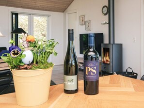 Una sala de estar con una mesa de madera, una planta en maceta, dos botellas de vino, una chimenea y un televisor.