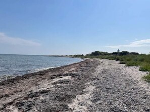 A beach with a rocky shoreline and a distant structure on the horizon. - 4 Star Holiday Home in Nordborg (Nordborg)
