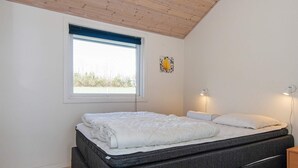 A bedroom with a bed, a window, a wall-mounted light, and a small bedside table. - 4 Star Holiday Home in Nordborg (Nordborg)