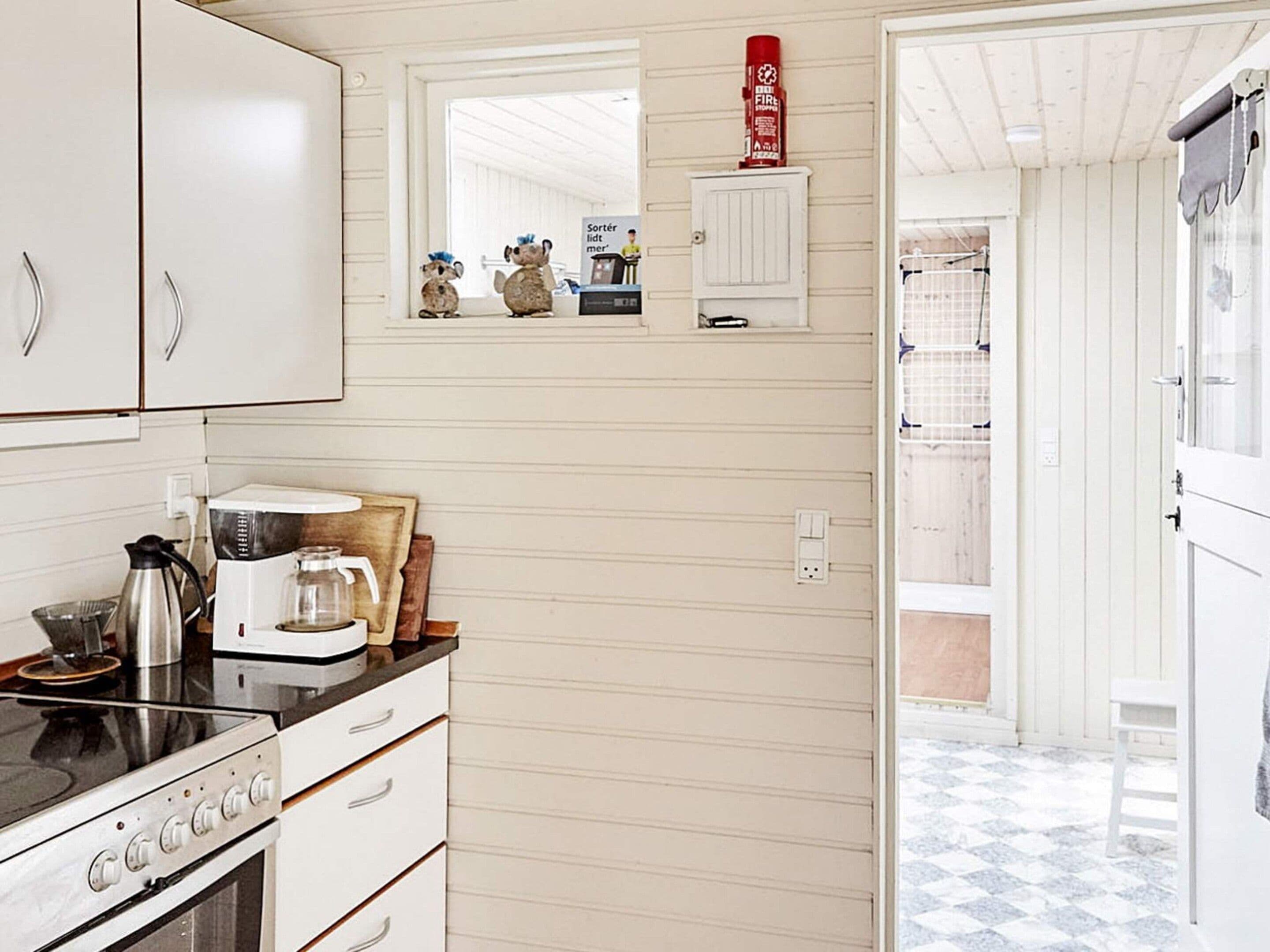 A kitchen with a stove, coffee maker, and a small shelf with decorative items.