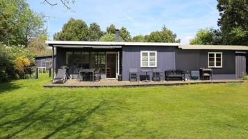A modern house with a patio, outdoor seating, and a covered area.