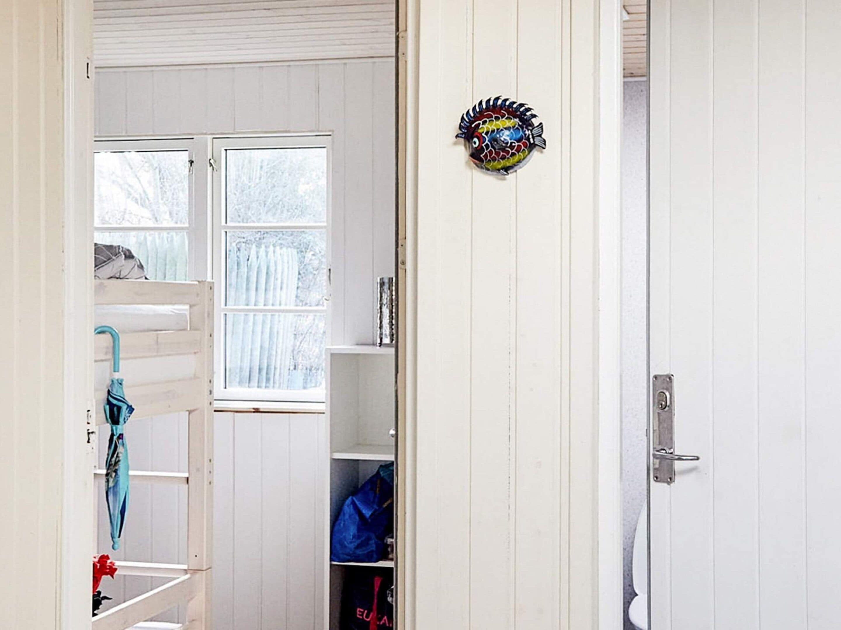 A room with a bunk bed, a window, a door, and a shelf with bags.