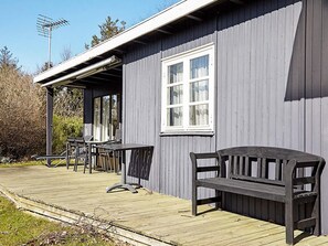 A wooden deck with a bench and tables, a covered area with a window, and an antenna on the roof. - 4 Person Holiday Home in Store Fuglede (Store Fuglede)