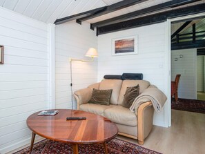 A room with a beige sofa, a wooden coffee table, a floor lamp, and a framed picture on the wall. - 5 Star Holiday Home in Haderslev (Haderslev)
