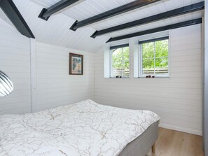 A bedroom with a bed, two windows, a framed picture on the wall, and a ceiling with exposed beams. - 5 Star Holiday Home in Haderslev (Haderslev)