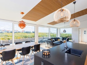 A modern kitchen with a central island, black chairs, and a dining table.