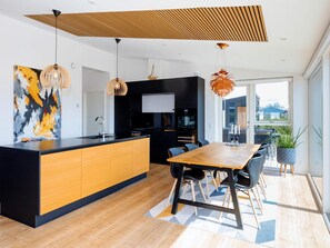 A modern kitchen with a central island, black cabinets, and a wooden dining table with chairs.