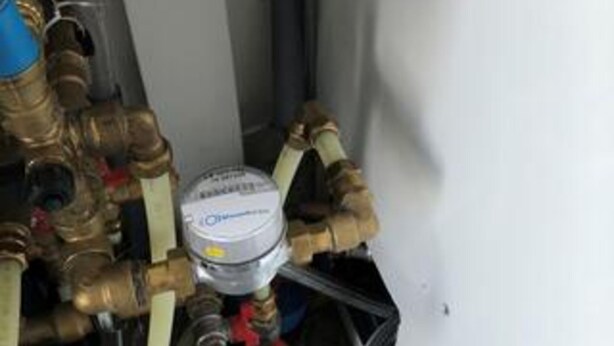 A water heater with brass pipes and a white label. - 5 Star Holiday Home in Lokken (Lokken)