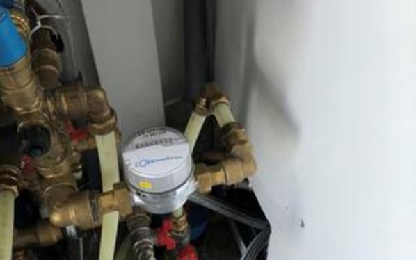 A water heater with brass pipes and a white label.