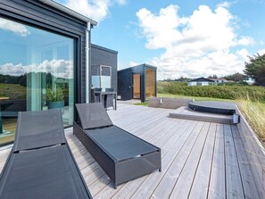 A modern outdoor deck with lounge chairs, a table, and a small seating area.