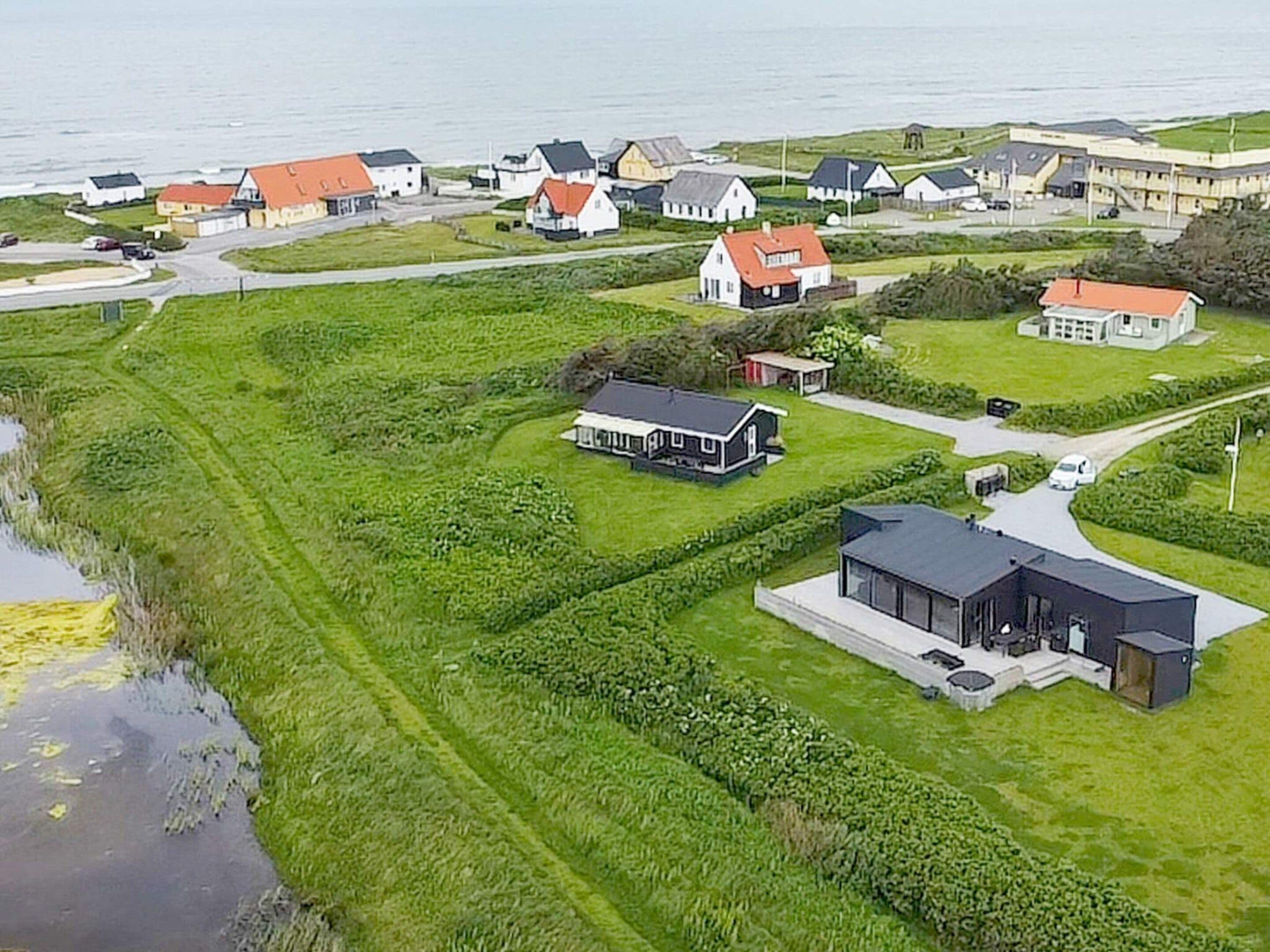 A coastal residential area with houses, a modern building, and a body of water.