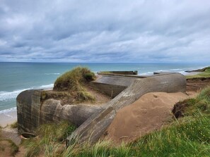 A coastal landscape with a concrete structure, grassy areas, and the sea.