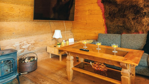 A cozy wooden room with a large TV mounted on the wall, a wooden table with glasses, and a rustic fur wall. - 8 Person Holiday Home in Ebeltoft (Ebeltoft)