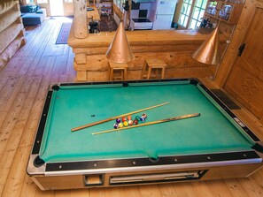 A pool table in a wooden cabin with a dining area and kitchen in the background. - 8 Person Holiday Home in Ebeltoft (Ebeltoft)
