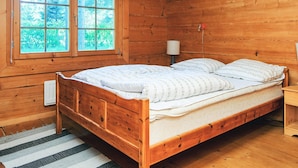 A wooden cabin bedroom with a bed, a window, and a lamp. - 8 Person Holiday Home in Ebeltoft (Ebeltoft)