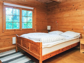 A wooden cabin bedroom with a bed, a window, and a lamp. - 8 Person Holiday Home in Ebeltoft (Ebeltoft)