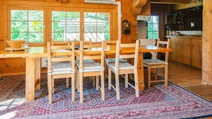 A wooden cabin interior with a dining area, kitchen, and large windows. - 8 Person Holiday Home in Ebeltoft (Ebeltoft)