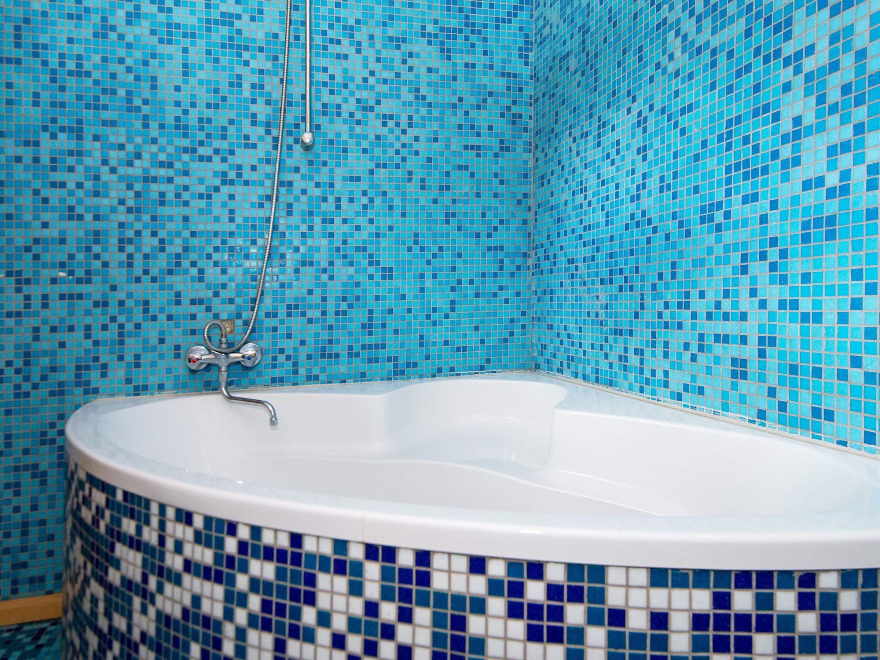 A bathtub with a showerhead in a room with tiled walls.