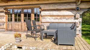 A log cabin with a porch, outdoor seating, and a stone wall. - 8 Person Holiday Home in Ebeltoft (Ebeltoft)