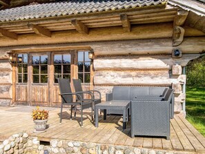 A log cabin with a porch, outdoor seating, and a stone wall. - 8 Person Holiday Home in Ebeltoft (Ebeltoft)