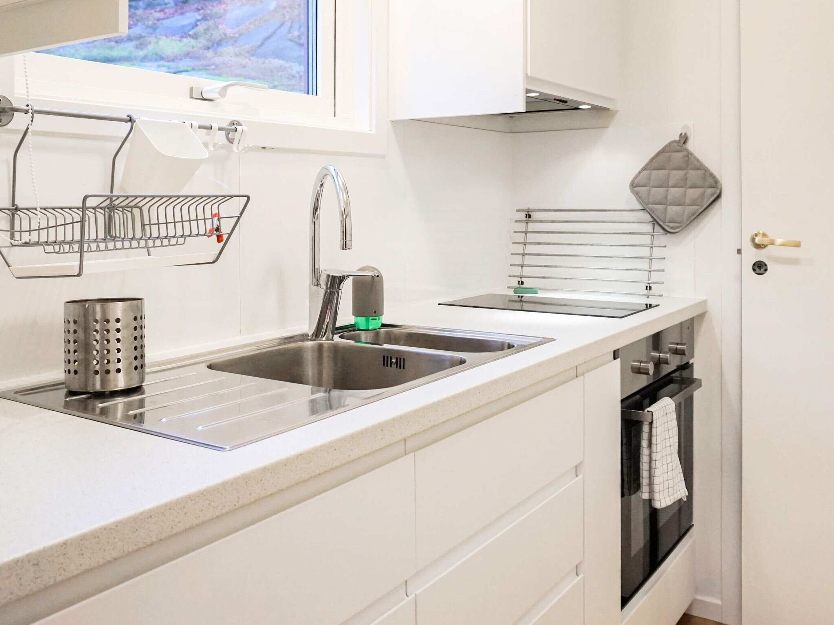 Una cucina con un lavello doppio, una cappa aspirante in acciaio inox e un forno integrato.