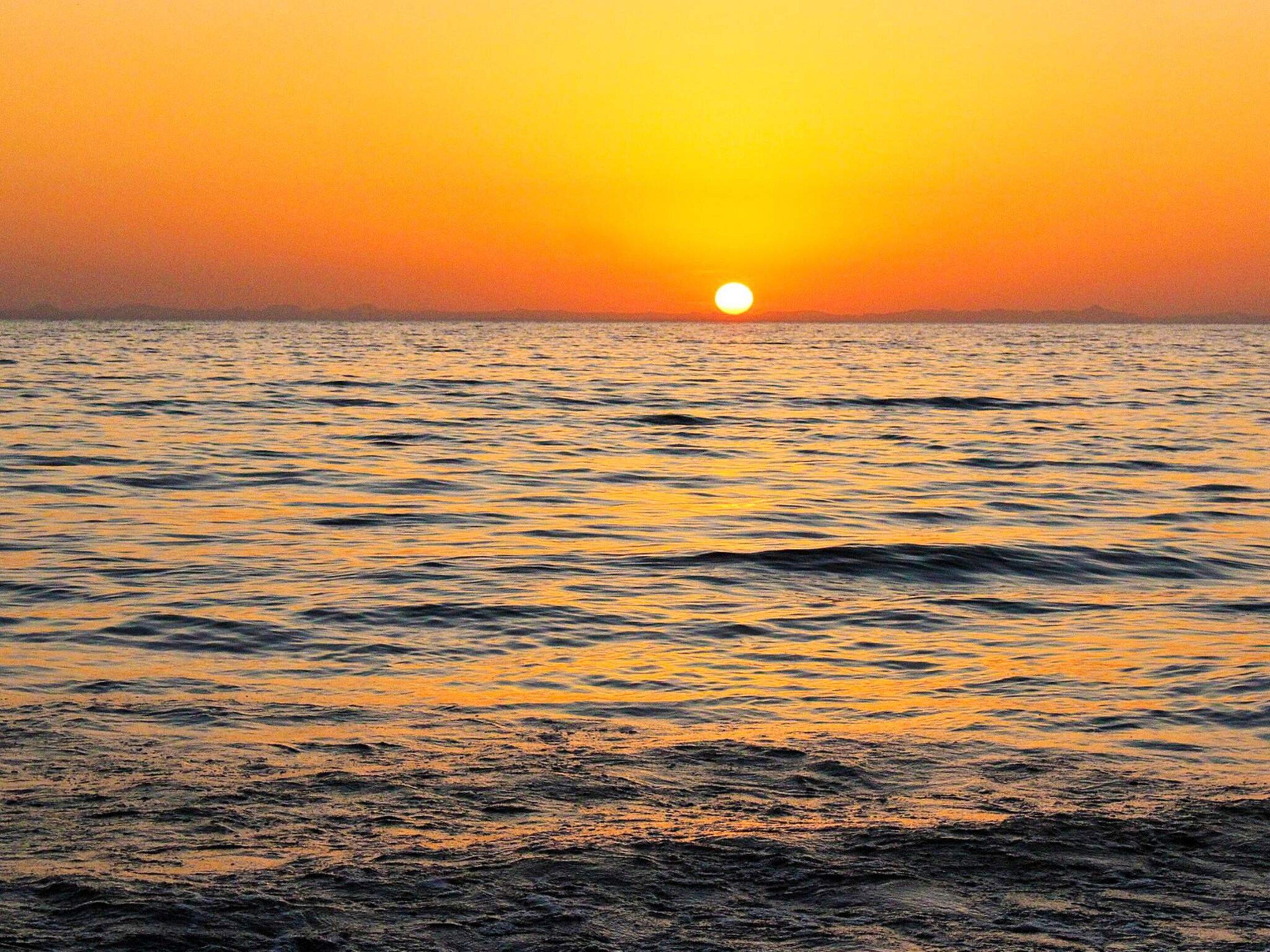 Ein Sonnenuntergang über einer Wasseroberfläche, ohne erkennbare Landmassen oder Bebauung.