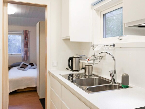A compact kitchenette with a double sink, a kettle, and a small window above the sink.