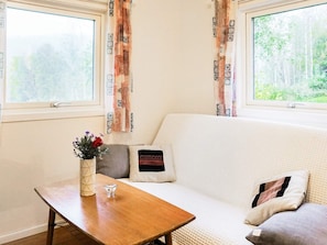 A cozy room with a sofa, a wooden table, and a vase with flowers.