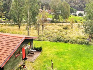 A green building with a red roof, a small patio with a table and chairs, and a grassy yard. - 3 Person Holiday Home in Henan (Henån)
