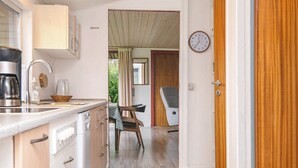 Una cucina compatta con macchina del caffè, lavello e zona pranzo con sedia e tavolo.