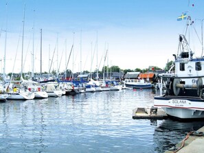 A marina with multiple sailboats docked, a large white boat named 'SOLANA' in the foreground, and a Swedish flag visible.