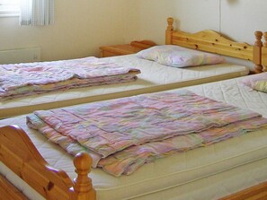 Two single beds with wooden headboards and a plain wall in the background.