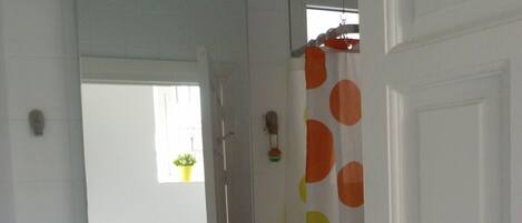 Une salle de bain avec un lavabo blanc, un miroir et un rideau de douche orné de pois orange et jaunes.