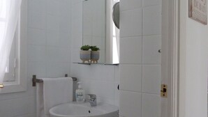 A bathroom with a white sink, a mirror, and a towel hanging on the wall. - Charming, very bright historic center (Sevilla)