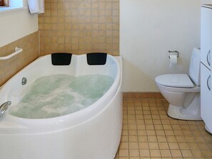 A bathroom with a bathtub, toilet, and tiled floor.