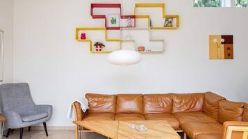 A living room with a brown leather sofa, a wooden coffee table, a gray armchair, and a red patterned rug.